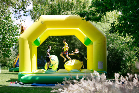 Niños jugando en un castillo inflable amarillo en Camping Seasonova Saint Michel en Normandía, Francia.
