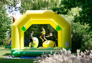 Bambini che giocano su un castello gonfiabile giallo al Camping Seasonova Saint Michel in Normandia, Francia.