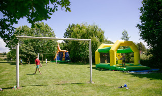 Niños juegan al fútbol y disfrutan de un castillo inflable en Camping Seasonova Saint Michel, Normandía, Francia.