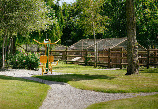 Buiten fitnesstoestel in een groene tuin van Camping Seasonova Saint Michel vakantiepark in Normandië, Frankrijk.