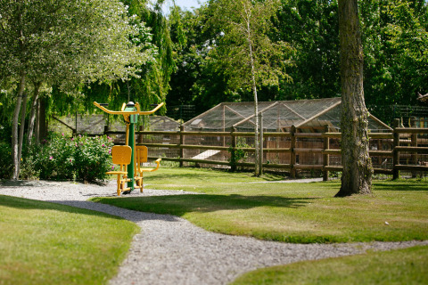 Outdoor exercise equipment set in a green garden at Camping Seasonova Saint Michel holiday park in Normandy, France.