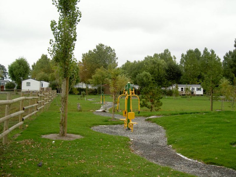 Fitnessgeräte im Freien am Camping Seasonova Saint Michel in der Normandie, Frankreich, mit viel Grün.