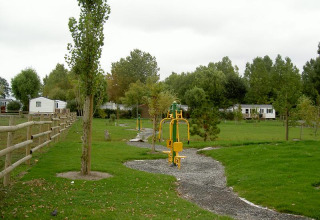 Outdoor fitness equipment at Camping Seasonova Saint Michel holiday park in Normandy, France, amidst greenery.