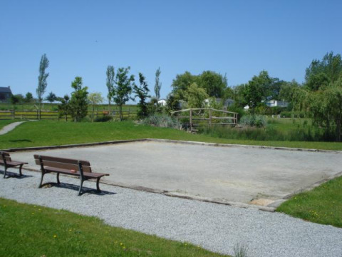 Camping Seasonova Saint Michel in der Normandie, Frankreich, mit Bouleplatz, Bänken und grüner Landschaft.