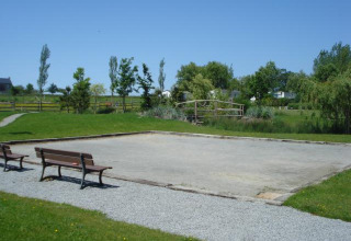 Camping Seasonova Saint Michel in Normandy, France, featuring a pétanque court, benches, and green views.