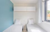 Bright Prestige Cottage room with two single beds, minimalist decor, and a large window with a view.