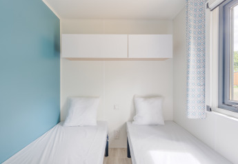 Modernes Zimmer im Prestige Cottage mit zwei Einzelbetten, blauem Akzentwand und großem Fenster.
