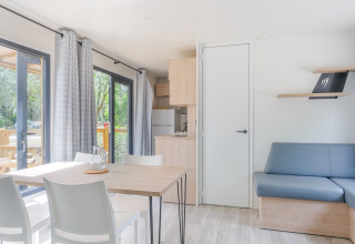 Bright and modern Prestige Cottage lodge with dining table, sofa, kitchen, and large windows to nature.