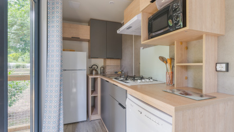 Cocina moderna en Prestige Cottage con estufa, microondas, nevera y vista al exterior verde.