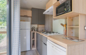 Cocina moderna en Prestige Cottage con estufa, microondas, nevera y vista al exterior verde.