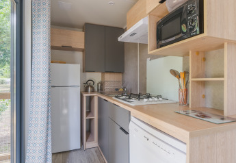 Moderne keuken in Prestige Cottage met fornuis, magnetron, koelkast en uitzicht op de tuin.