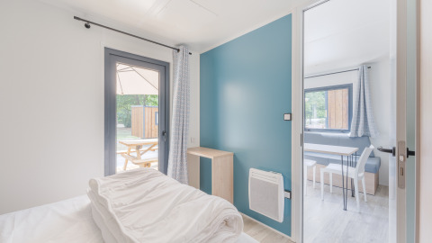 Chambre de lodge lumineuse et moderne avec vue sur coin repas et terrasse extérieure avec table.
