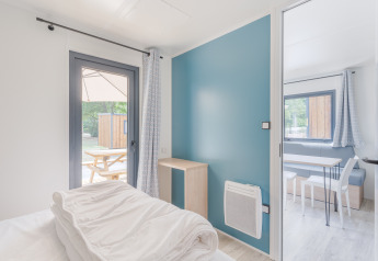 Lichte moderne lodgekamer met zicht op kleine eethoek en buiten terras met picknicktafel.