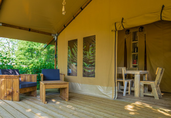 Deck of Slow Lodge safari tent featuring wooden outdoor seating and dining area entrance inside tent.