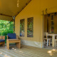 Terraza exterior del safari tent Slow Lodge con asientos de madera y entrada al comedor del interior.