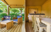 Safari tent at Slow Lodge with wooden furniture, covered patio, and relaxing outdoor seating area.