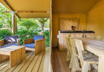 Tenda safari allo Slow Lodge con mobili in legno, veranda coperta e confortevole area salotto esterna.