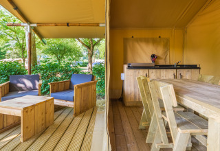 Tenda safari allo Slow Lodge con mobili in legno, veranda coperta e confortevole area salotto esterna.