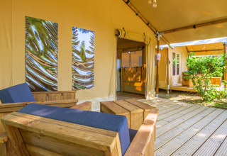 Acogedora zona de descanso en la tienda safari Slow Lodge con muebles de madera y vista al jardín.