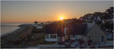 Sonnenuntergang über Camping Seasonova Les 7 Iles an der Küste der Bretagne, Frankreich, mit Restaurant.