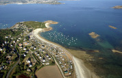 Luftfoto af Camping Seasonova Les 7 Iles i Bretagne, Frankrig, med stranden, campingvogne og havudsigt.