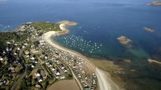 Luchtfoto van Camping Seasonova Les 7 Iles in Bretagne, Frankrijk, met strand, huisjes en boten aan de kust.