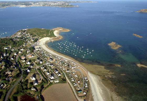 Luftfoto af Camping Seasonova Les 7 Iles i Bretagne, Frankrig, med stranden, campingvogne og havudsigt.