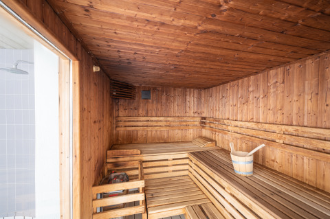 Houten sauna met zitbanken en emmer, highlight van Camping Seasonova Les Vosges du Nord in Frankrijk.