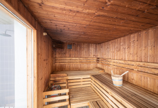Houten sauna met zitbanken en emmer, highlight van Camping Seasonova Les Vosges du Nord in Frankrijk.