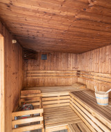Sauna de madera con bancos y cubo, uno de los atractivos de Camping Seasonova Les Vosges du Nord en Francia.