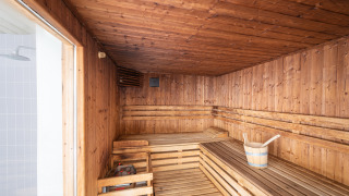 Sauna de madera con bancos y cubo, uno de los atractivos de Camping Seasonova Les Vosges du Nord en Francia.