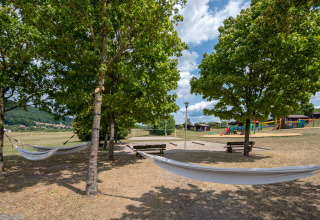Buitenkampeerterrein met hangmatten tussen bomen, banken en speeltuin in Les Vosges du Nord, Frankrijk.