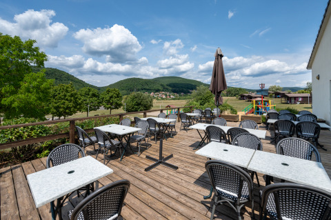Buitenterras met tafels en stoelen op Camping Seasonova Les Vosges du Nord, Grand Est, Frankrijk.