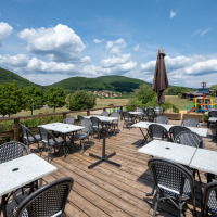 Buitenterras met tafels en stoelen bij Camping Seasonova Les Vosges du Nord, Grand Est, Frankrijk.