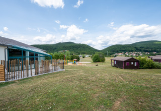 Vista del Camping Seasonova Les Vosges du Nord con colline verdi, area giochi e cabine in Grand Est, Francia.
