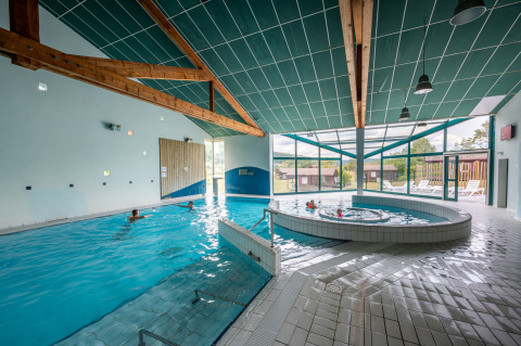 Piscina coperta con jacuzzi e grandi finestre al Camping Seasonova Les Vosges du Nord, Grand Est, Francia.