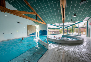 Binnenzwembad met jacuzzi en grote ramen bij Camping Seasonova Les Vosges du Nord, Grand Est, Frankrijk.