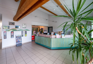 Ontvangst van Camping Seasonova Les Vosges du Nord met planten en houten balken in Grand Est, Frankrijk.