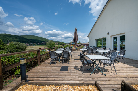 Terraza exterior con mesas y sillas en Camping Seasonova Les Vosges du Nord, Grand Est, Francia.