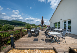 Terrazza all'aperto con tavoli e sedie presso Camping Seasonova Les Vosges du Nord in Grand Est, Francia.