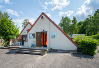 Toiletgebouw op Camping Seasonova Les Vosges du Nord, omgeven door natuur en bomen, Grand Est, Frankrijk.