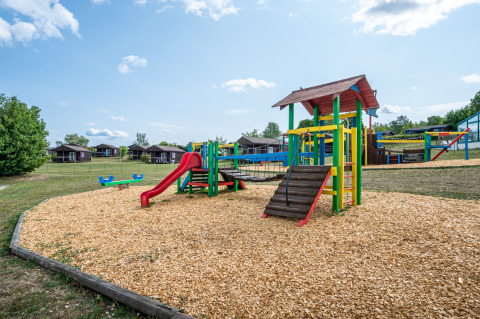 Playground with colorful play equipment and slide at Camping Seasonova Les Vosges du Nord in Grand Est, France.