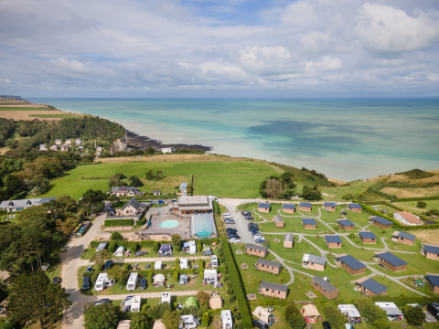 Vista aérea del parque vacacional Huttopia Les Falaises con cabañas y zona de camping en Normandía, Francia.