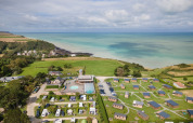 Luftfoto af ferieparken Huttopia Les Falaises med hytter og campingplads ved kysten i Normandiet, Frankrig.