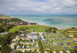Luftaufnahme vom Ferienpark Huttopia Les Falaises mit Hütten und Camping in Normandie, Frankreich, am Meer.