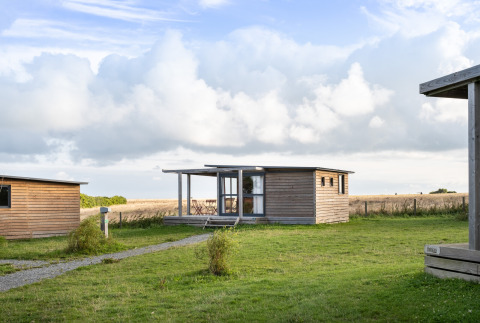 Acogedora cabaña de madera en Huttopia Les Falaises - Normandie, rodeada de prados y naturaleza en Normandía.