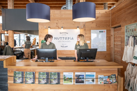 Personal de recepción da la bienvenida a los huéspedes en Huttopia Les Falaises, un parque de vacaciones en Normandía.
