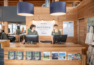 Receptiemedewerkers verwelkomen gasten bij Huttopia Les Falaises, een vakantiepark in Normandië, Frankrijk.