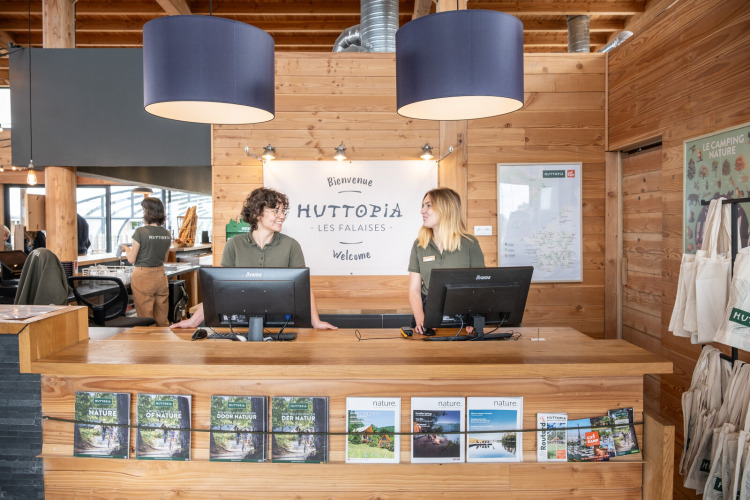 Le personnel d’accueil reçoit les visiteurs à la réception du parc de vacances Huttopia Les Falaises en Normandie.
