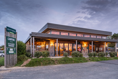 Huttopia Les Falaises camping in Normandië, Frankrijk, verlicht paviljoen bij avondschemer.